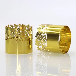 Close-up of laser-cut gold floral napkin rings with reflective mirror finish on white background