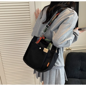 Detail of black canvas tote bag with vibrant ethnic style embroidered shoulder straps