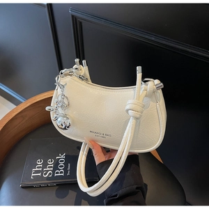 Detail of white wrinkled faux leather bag with silver charms and logo printing