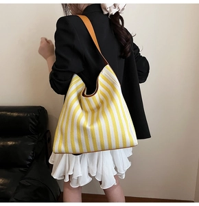 Detail of yellow and white striped canvas tote bag with brown leather shoulder strap