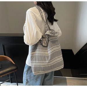 Détail d'un sac cabas en toile à carreaux vichy noir et blanc porté par un mannequin