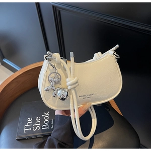 Detail of white pleated leather moon bag featuring silver balloon dog charm