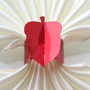 Detail of red apple napkin ring with metallic gloss on cream satin cloth