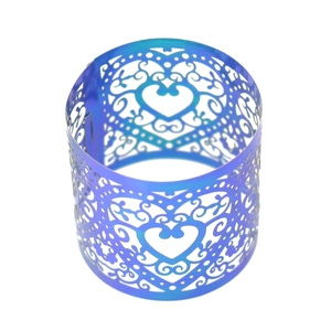 Macro view of blue-purple laser-cut metal napkin ring with intricate heart patterns