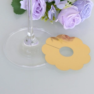 Detail of gold petal-shaped wine glass name tags on a white surface with roses