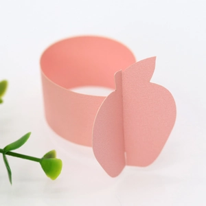 Detail of pink pearlescent paper napkin ring with a minimalist apple-shaped cut-out design