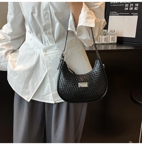 Model wearing a black woven leather crescent bag with white shirt and grey trousers