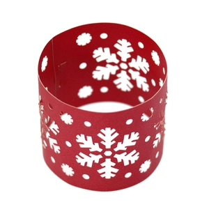 Macro detail of red paper napkin ring featuring laser-cut snowflake and dot patterns