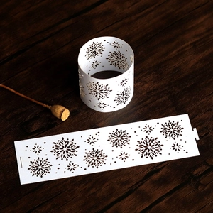 Detail of white laser-cut snowflake paper napkin ring on a dark rustic wood background