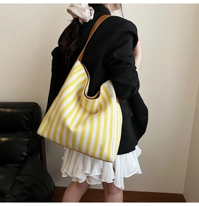 Detail view of the yellow striped canvas tote bag with premium brown leather strap