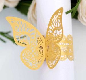 Macro detail of laser-cut butterfly napkin ring in matte gold with intricate mesh texture