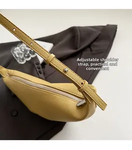 Detail view of adjustable leather strap and silver buckle on yellow crescent bag