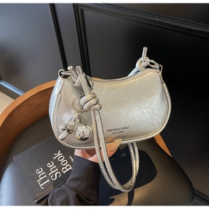 Detail of silver pleated texture shoulder bag with knot strap and metallic dog charm