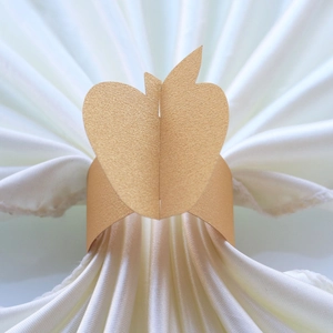 Close-up of golden apple napkin ring with pearlescent finish on white silk fabric