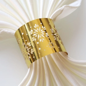 Macro shot of gold laser-cut snowflake napkin ring with elegant white satin cloth detail