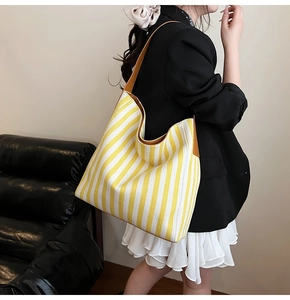Detail of yellow and white striped hobo tote bag with brown leather strap detail