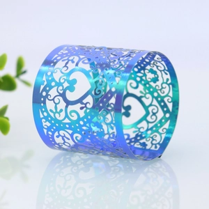 Macro detail of iridescent blue heart napkin ring with laser-cut floral patterns