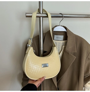 Detail of light yellow crescent shoulder bag featuring crocodile embossed leather texture