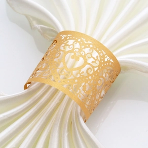 Detailed close-up of golden laser-cut heart napkin rings on white satin fabric