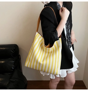 Detail of yellow and white striped canvas tote bag with brown leather shoulder strap