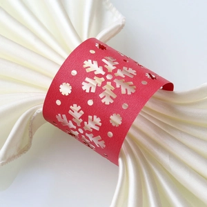 Macro shot of red snowflake cutout paper napkin ring on white satin fabric decoration