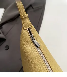 Detailed close-up of smooth silver zipper on yellow pebbled leather dumpling bag