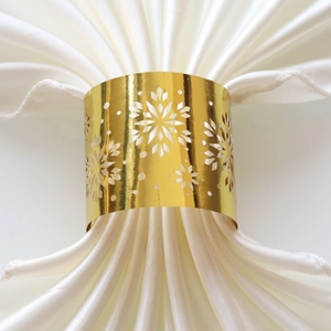 Detail of laser-cut gold snowflake napkin ring on elegant white satin fabric