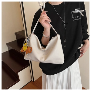 Detailed view of white lychee leather hobo bag featuring a cute elephant charm pendant