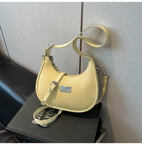 Close-up of yellow crocodile embossed half-moon bag with silver metal plaque detail