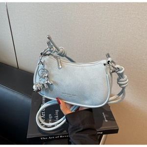 Detail of light blue pleated hobo bag with knotted shoulder strap and silver dog charm