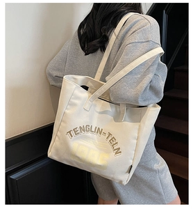 Grand sac cabas en toile beige avec impression de lettres porté sur l'épaule