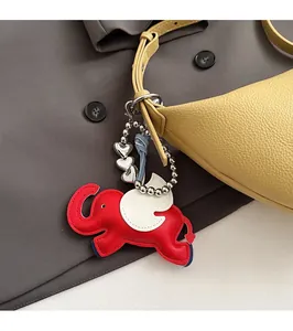 Detail of red elephant bag charm with white wings on a yellow leather shoulder bag