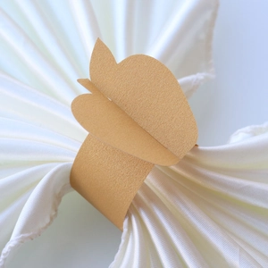 Close-up of golden butterfly napkin ring with pearlescent finish on white silk cloth