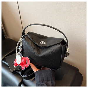 Détail du sac à main noir avec texture litchi et un pendentif éléphant mignon