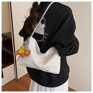 White lychee leather shoulder bag with a cute cartoon elephant charm on a model