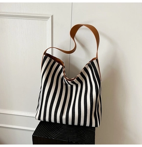 Detail of a large black and white striped canvas tote bag with brown leather straps