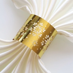 Detailed close-up of a golden snowflake napkin ring with intricate laser-cut metal patterns