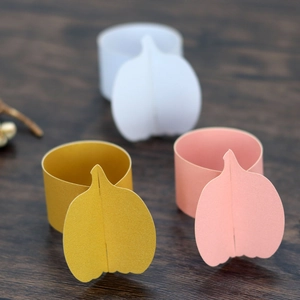 Detail showing laser-cut pumpkin napkin rings in mustard yellow, pink, and white paper
