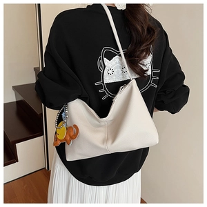 Detail view of cream white lychee leather hobo bag with a cute orange elephant charm