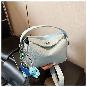 Détail d'un sac à main en cuir grainé bleu clair avec fermoir rotatif et breloque éléphant