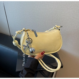 Close-up of pale yellow moon bag with silver ball charm and cute balloon dog pendant