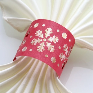 Close-up of red laser-cut snowflake paper napkin ring with white satin fabric
