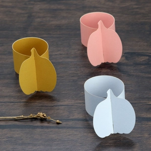 Three-dimensional paper pumpkin napkin rings in yellow, pink, and blue for table decor
