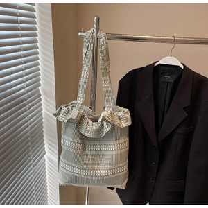Détail du sac cabas en toile à carreaux vert et blanc avec bords volantés sur cintre