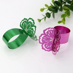 Macro detail of hollowed butterfly napkin rings in emerald green and rose purple finishes