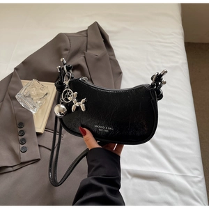 Detail of black patent leather hobo bag with silver dog charm and MIKAXIOI logo