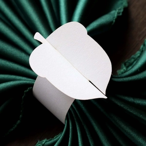 Macro view of white laser-cut paper napkin rings with elegant leaf design for weddings