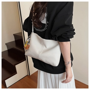 Detail view of white lychee texture tote bag with horse pendant and vertical stitching
