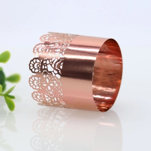 Macro shot of rose gold lace cut napkin ring with mirror finish on reflective surface