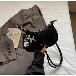 Detail of black patent leather hobo bag with pleated texture and silver balloon dog charm